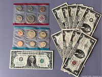 Two 1972 US Mint uncirculated coin sets in sealed plastic packages with coins and nine $2 bills plus one $1 bill spread for view
