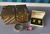 Vintage men's jewelry and accessories with brass expandable organizer and jewelry box on blue surface