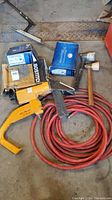 Photo showing entire lot including Bostitch stapler, several staple boxes, red air hose, and two mallets.