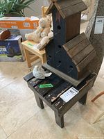 Wooden multi birdhouse on small wooden stool with white ceramic bird figurine sitting on the stool