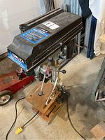 Full view of Delta drill press including base, table, and motor housing showing brand and condition.