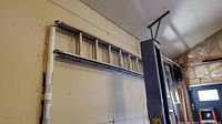 Full-length view of folded extension ladder mounted on wall