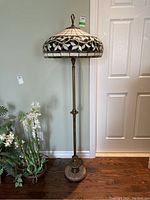 Full view of the floor lamp showing Tiffany style stained glass shade, brass-colored metal stand, and stone base.