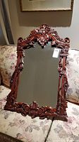 Front angled view of the vintage mahogany wall mirror showcasing detailed carving and overall condition.