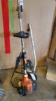 Full view of the gas trimmer with edger attached, including carrying strap and throttle handle.