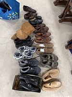 Full view of all shoes laid out on concrete floor showing variety of styles and colors including boots, casual shoes, sneakers, and sandals.