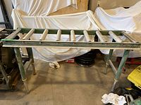 Full view of the roller support table showing the metal frame, rollers, and adjustable legs.