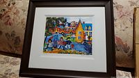 Framed limited edition print showing colorful scene of children carrying golf bags near houses and a parked car.