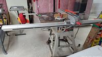 Front angle view of table saw on stand showing sliding aluminum fence rails and cast-iron table surface