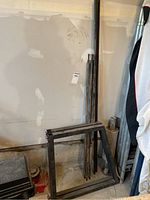 Disassembled tire rack frame and long support bars laid out in garage corner.