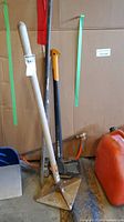 Photo showing 10x10 tamper, Fiskars X27 splitting axe with orange handle, and other tools stored in garage.