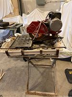 Full view of MK 101 wet saw on folding stand showing cutting platform, power cords and water lines.