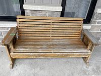 Front view of wooden bench with horizontal wood slats, showing wear and surface discoloration.