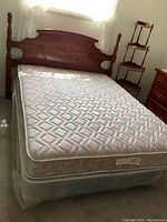 Full view of assembled bed with solid wood headboard, side rails, and mattress with quilted cover.