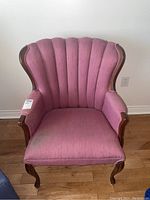 Front view of the pink upholstered accent chair with wood frame and curved legs.