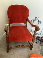 Full front view of vintage wooden framed chair with red velour upholstery