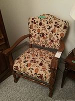 Front angle view of a vintage wooden armchair with floral fabric upholstery, showing carved armrests and floral pattern on fabric.