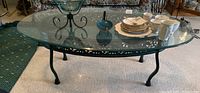 Full view of rectangular glass top coffee table with items on glass surface showing clear top and metal frame details
