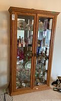 Full front view of the wood display cabinet showing glass double doors and visible displayed items inside.