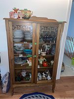 Full front view of wooden display case filled with various dishware and decorative items inside.