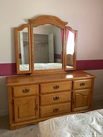 Full view of solid wood dresser with tri-fold mirror on top, showing drawer and cabinet details.