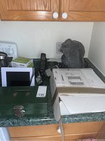 Overview of all items on kitchen counter including digital calendar, cordless phones, lock box, and packed Alto phone