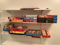 Wide shot of multiple jigsaw puzzle boxes (1000-piece) arranged on shelves with boxed board games underneath.
