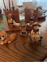 Wide view of the lot showing all figurines and bookends on a wooden table.