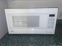 Front and side view of LG white microwave oven on a kitchen counter.