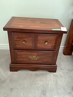 Front view of the solid wood nightstand with two small drawers on top and one large drawer on bottom, showing metal pulls and the natural wood finish.