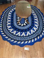 Oval shaped blue, black, white, and grey rope rug under coffee table on wooden floor