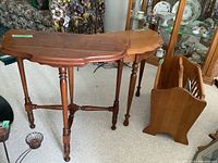 Two demi lune wood side tables with scalloped edges and turned legs, shown together with wood magazine rack