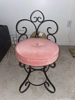 Full view of the vanity chair showing the metal base and pink cushion seat.