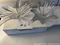 Two clear glass bowls with wide star or flower pattern edges on a white surface, showcasing their shape and design.