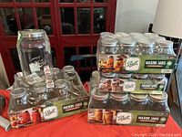 Two sealed 12-pack boxes of Ball mason jars: 12 quart jars and 12 pint jars, stacked with one gallon jar on the side