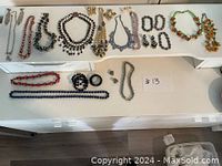 Full layout of all jewelry items including necklaces, earrings, and bracelets on white surface with lot number #13 visible.