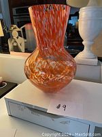Full view of the vase showing the bulbous bottom and flared neck with orange swirl pattern.