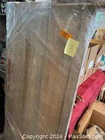 Headboard and footboard completely wrapped in plastic, standing vertically, showing wooden panels with smooth surfaces.