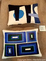 Set of two Jonathan Adler pillows showing the Rio Arches and Milano Emerald/Navy Blocks patterns side by side on beige fabric.