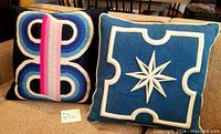Both Jonathan Adler pillows side by side on a couch showing full front designs.