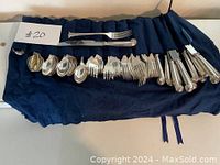 Assortment of silverplated forks, spoons and knives laid out on cloth