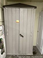 Full front view of the grey taupe garden shed with brown peaked roof, closed double doors with handle and lock base.