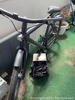 Front quarter view of VanMoof S3 with charger box and cables on green balcony flooring