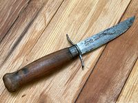 Photo showing full length of one Frosts knife with wood handle and laminated steel blade, resting on wood floor