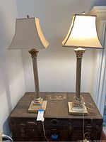 Pair of matching table lamps on wooden chest, showing full height and design