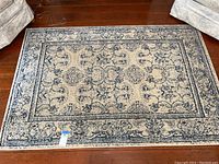 Full view of rectangular wool-like patterned area rug on wooden floor, showing overall condition and design.