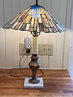 Full view of the stained glass table lamp on a wood surface against a white panel wall.