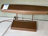 Front perspective view showing the full lamp with horizontal tubular shade and attached cord on a white surface.