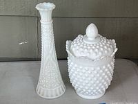 9-inch milk glass bud vase and 7.5-inch hobnail covered jar side by side showing overall shapes and details