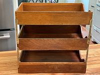 Front view of vintage three tier wood file box showing the wood trays and metal uprights.